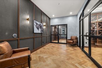 A hallway with a brown leather chair and a wooden floor.